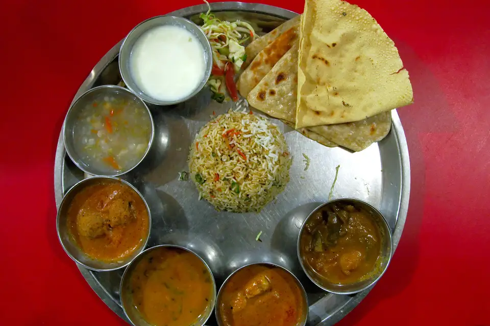 Um thali servido em prato de metal, com arroz, pão e várias cumbucas de molho